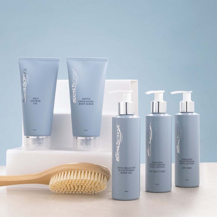 Beauté Pacifique Body Care 200 ml der giver fugt i lyseblå tuber og pumpeflasker med sølvdetaljer og træbørste