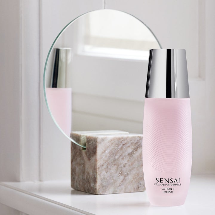 Sensai Cellular Performance Lotion II Moist fugtgivende ansigtslotion i lyserød flaske foran et spejl