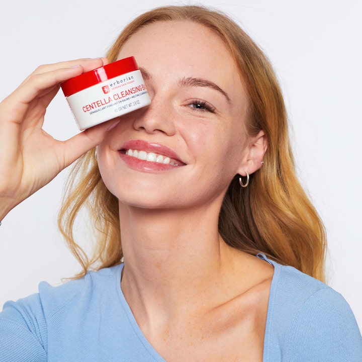 Erborian Centella Cleansing Balm 80 g ansigtsrens som holdes af en smilende kvinde foran øjet