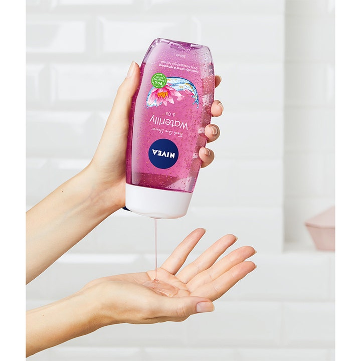 NIVEA Caring Shower Gel Waterlily & Oil 250 ml hældes ud i hånden og viser den lyserøde gel med olieperler.