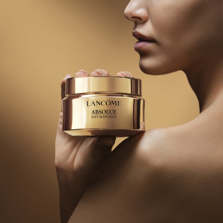 Lancôme Absolue Soft Body Balm 200 ml nærende bodylotion i en luksuriøs guldkrukke mod en kvindes skulder