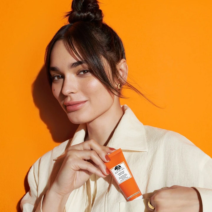 Origins GinZing SPF40 Energy-Boosting Tinted Moisturizer 50 ml tonet solcreme i orange tube holdt af kvinde