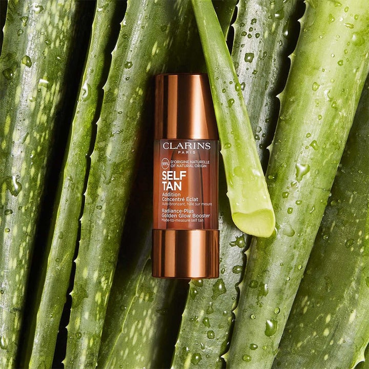 Clarins Golden Glow Booster selvbruner dråber der giver glød i bronze flaske blandt grønne aloe vera blade