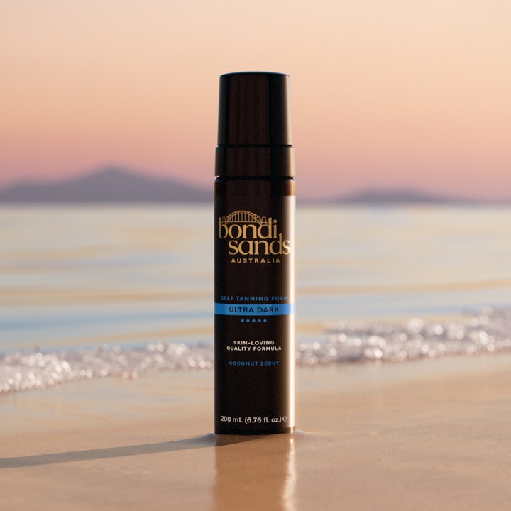 Bondi Sands Self Tanning Foam Ultra Dark 200 ml selvbruner giver mørk glød i sort flaske på en strand ved solnedgang