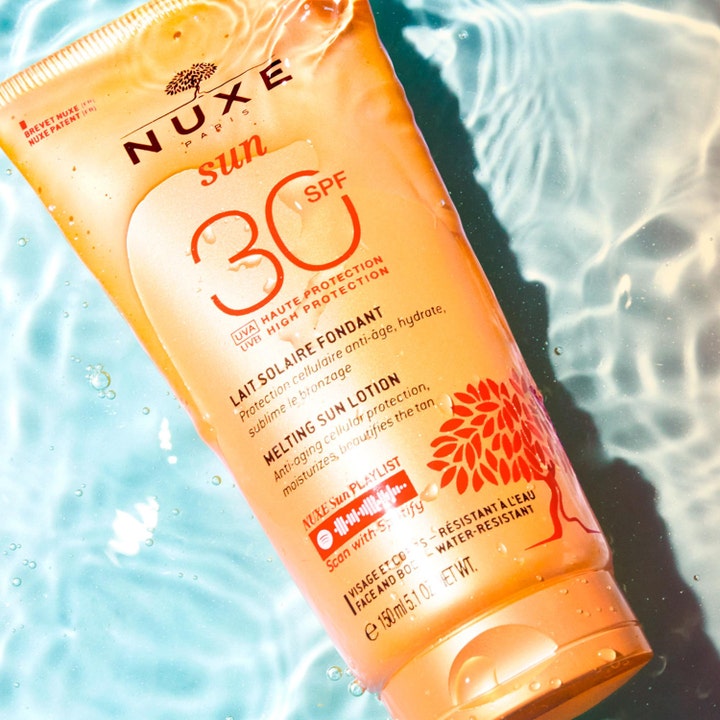 Nuxe Sun Melting Sun Lotion SPF30 150 ml fugtgivende solcreme i orange tube nedsænket i klart vand