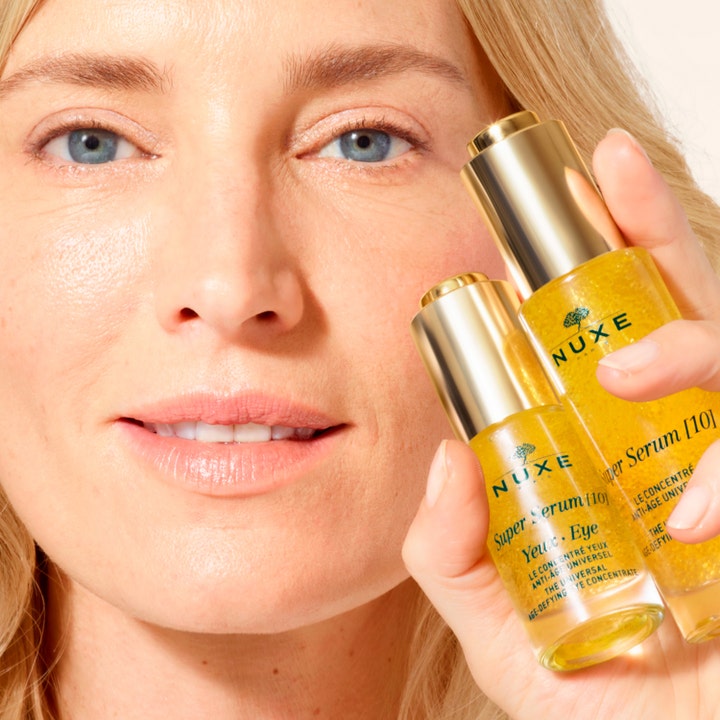 Nuxe Super Serum [10] Eye 15 ml anti-age øjenserum med synlige gyldne mikrokugler holdt af en kvinde