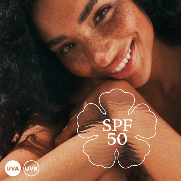 Hawaiian Tropic Glowing Protection Face Lotion 50 ml solcreme giver glød vist på smilende kvinde med SPF 50 og UVA UVB.