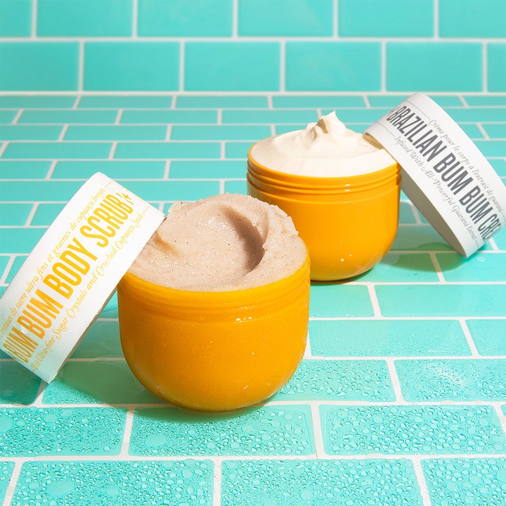 Sol de Janeiro Bum Bum Body Scrub 220 g eksfolierende body scrub i gul krukke med kornet tekstur på blå fliser