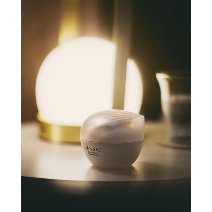 Sensai Comforting Barrier Mask 60 ml beroligende ansigtsmaske i elegant krukke ved siden af en varm lampe