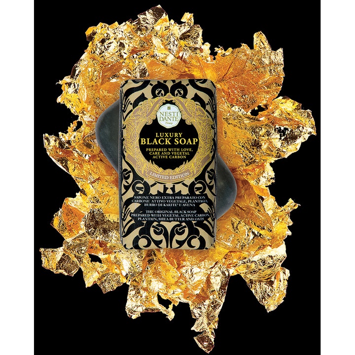 Nesti Dante Luxury Black Soap 250 ml fast håndsæbe med aktivt kul i guldindpakning på en baggrund af bladguld