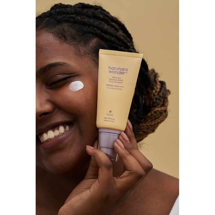 haruharu wonder Black Rice Moisture Airyfit Daily Sunscreen 50 ml fugtgivende solcreme SPF 50 i gul tube og creme på kinden