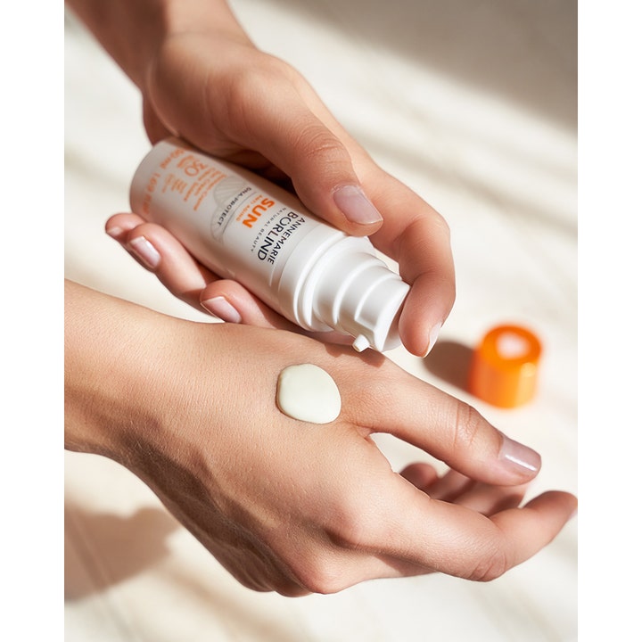 Annemarie Börlind Sun DNA Protect 50 ml solcreme påføres som en cremet tekstur på hånden fra en hvid pumpeflaske.