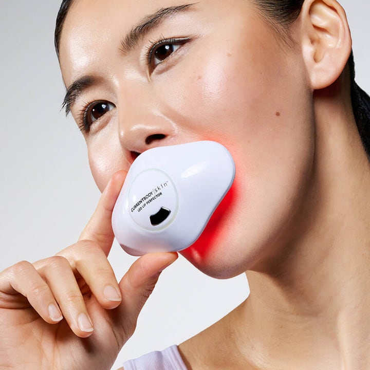 Currentbody Skin LED Lip Perfector anti-age læbebehandling anvendt af kvinde med lysende rødt LED-lys