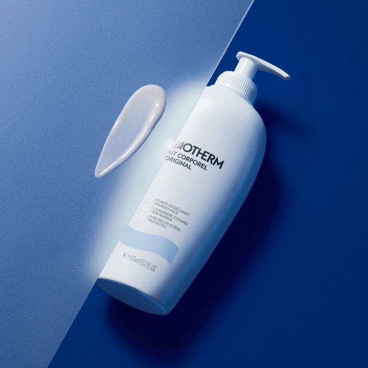 Biotherm Lait Corporel 400 ml fugtgivende body lotion i hvid pumpeflaske med cremet teksturprøve på blå baggrund