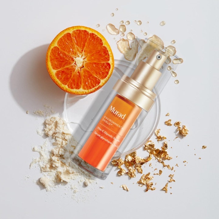 Murad Vita-C Glycolic Serum 30 ml lysnende serum med C-vitamin vist med en appelsin og guldflager