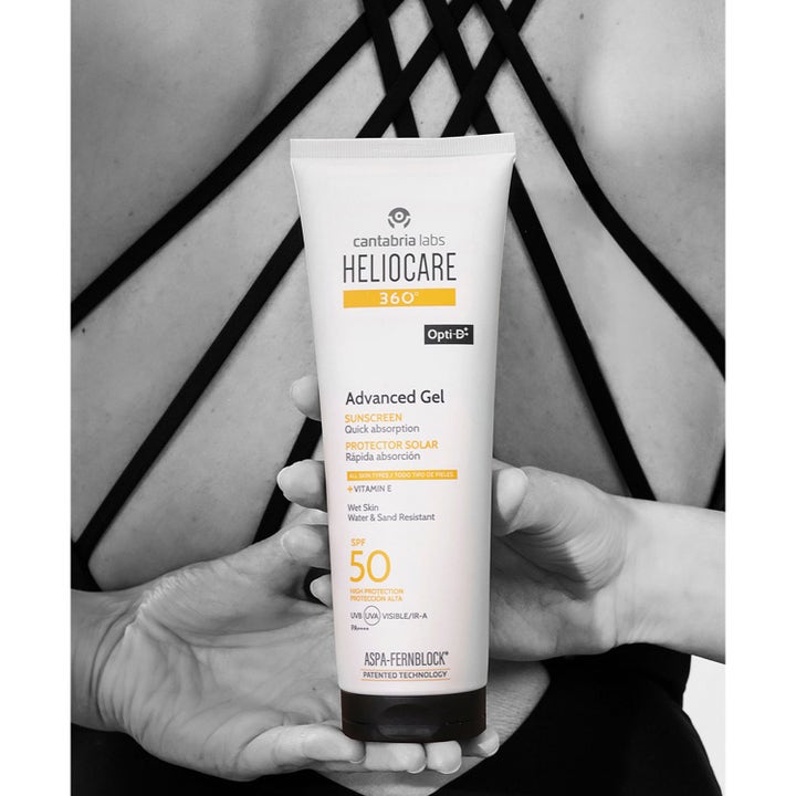 Heliocare Advanced Gel 250 ml SPF 50 solcreme med E-vitamin i hvid tube holdt mod en bar ryg.