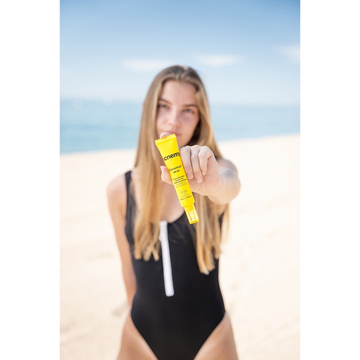 Niche Beauty Lab Acnemy Zitcontrol SPF 50 40 ml dagcreme mod urenheder i gul tube vist på en strand.