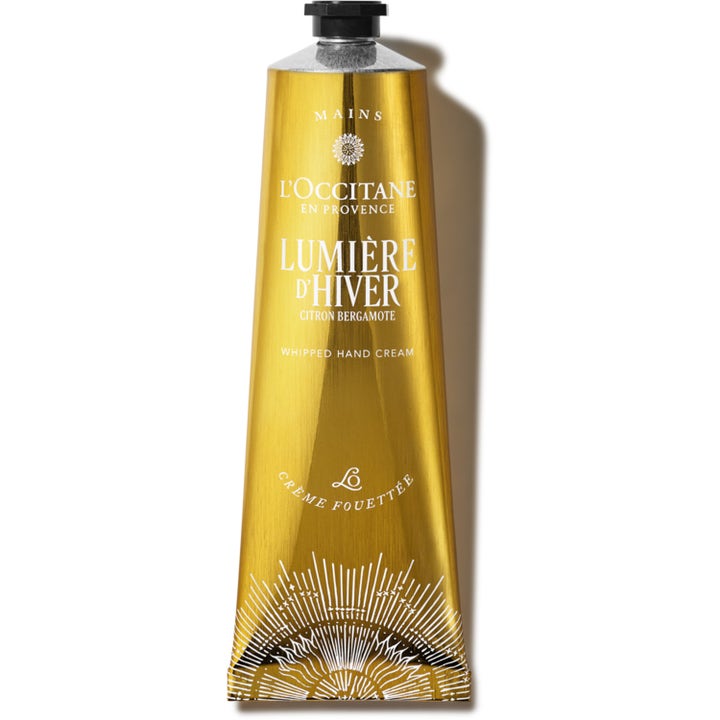 L'Occitane Lumière d'Hiver Whipped Hand Cream blødgørende håndcreme i en strålende guld-tube med sort skruelåg.