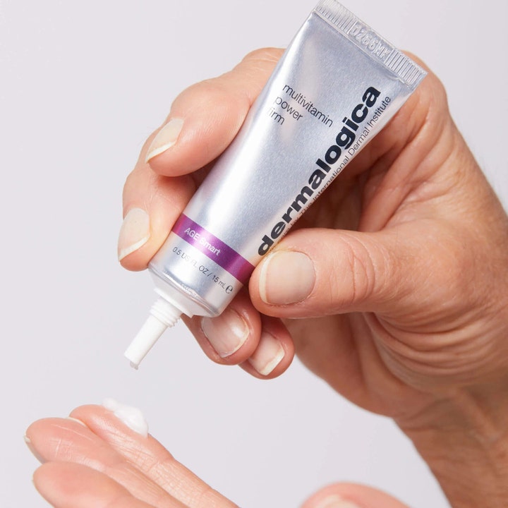 Dermalogica AGE smart Multivitamin Power Firm 15 ml opstrammende øjencreme i sølvfarvet tube trykkes ud i hånden.