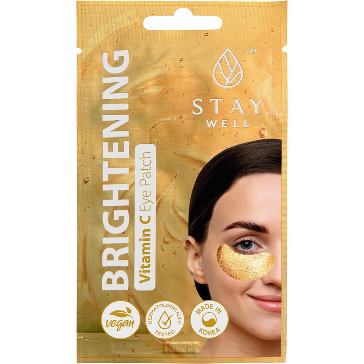 Stay Well Brightening Vitamin C Eye Patch 1 par oplysende øjenmaske i guldsachet med kvinde iført guld-patches.