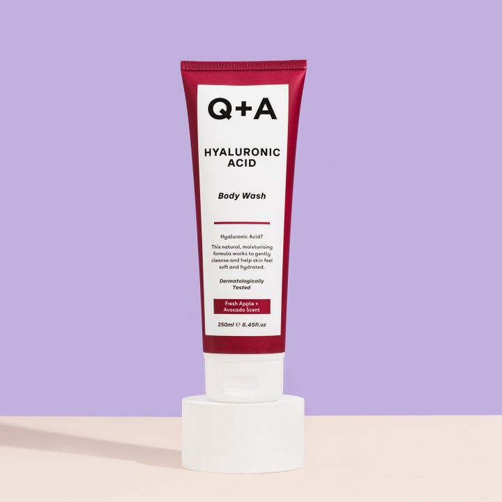 Q+A Hyaluronic Acid Body Wash 250 ml fugtgivende badesæbe i mørkerød tube stående på en hvid sokkel
