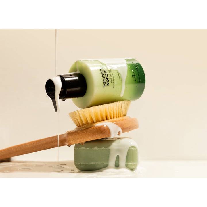 haruharu wonder Black Bamboo Daily Smoothing Body Oil 200 ml kropspleje med hvid mælket olie over grøn flaske og træbørste