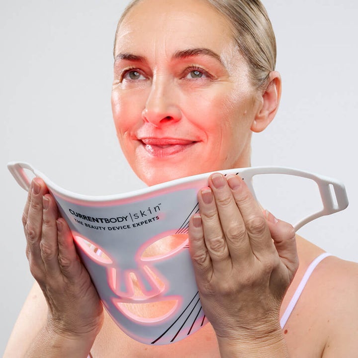 Currentbody Skin LED Light Therapy Face Mask Series 1 anti-ageing LED-maske holdt af kvinde med glødende rødt lys