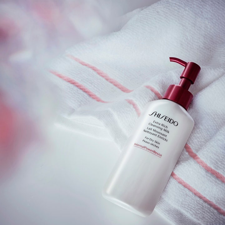 Shiseido Defend Extra Rich Cleansing Milk 125 ml fugtgivende ansigtsrens hvid flaske med rød pumpe på et blødt håndklæde