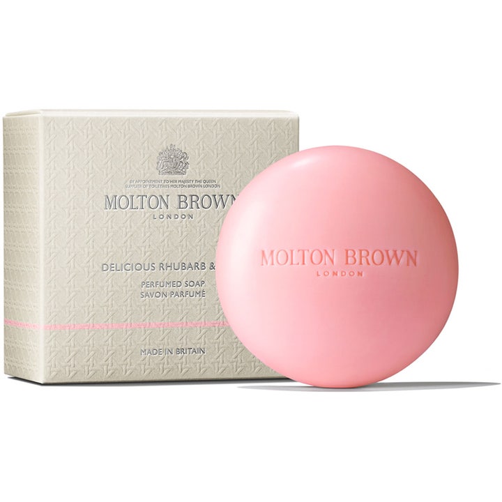 Molton Brown Delicious Rhubarb & Rose 150 g vellugtende håndsæbe er en rund lyserød fast sæbe ved sin mønstrede æske.