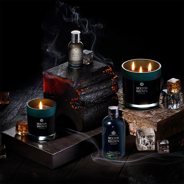 Molton Brown Dark Leather Bath & Shower Gel 300 ml showergel i en stemningsfuld opstilling med tændte lys og røg