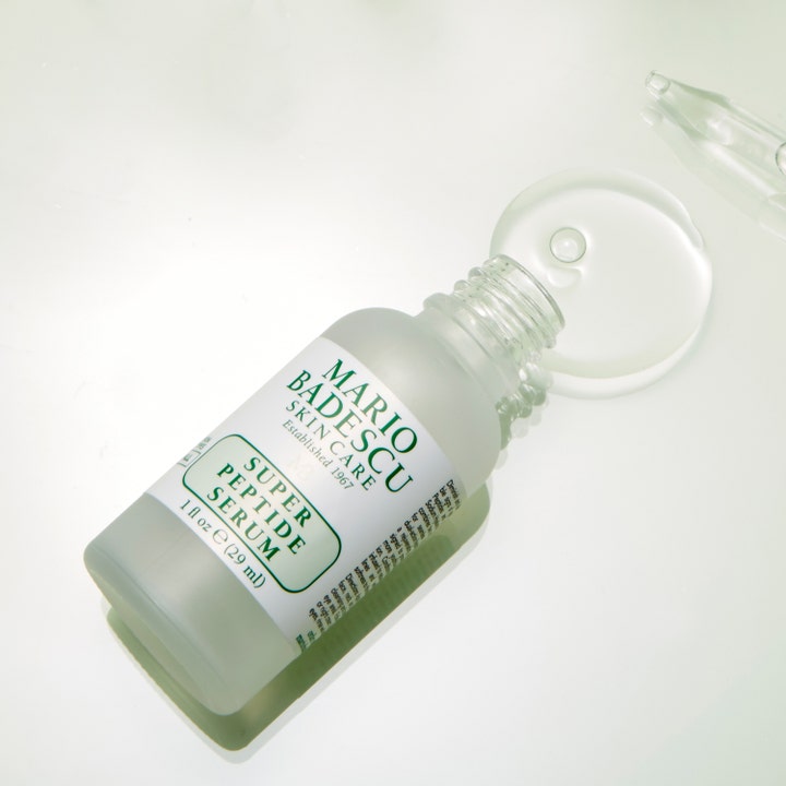Mario Badescu Super Peptide Serum 29 ml ansigtsserum viser sin klare, lette tekstur flyde fra en frostet glasflaske.