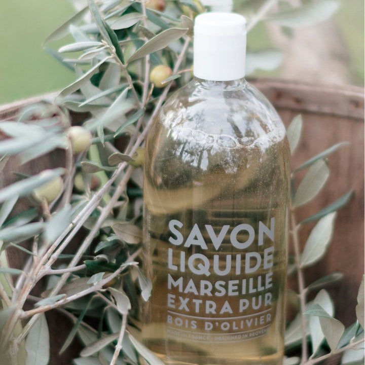 Compagnie de Provence Liquid Marseille Soap Olive Wood 1000 ml refil i gennemsigtig flaske ved olivengrene.