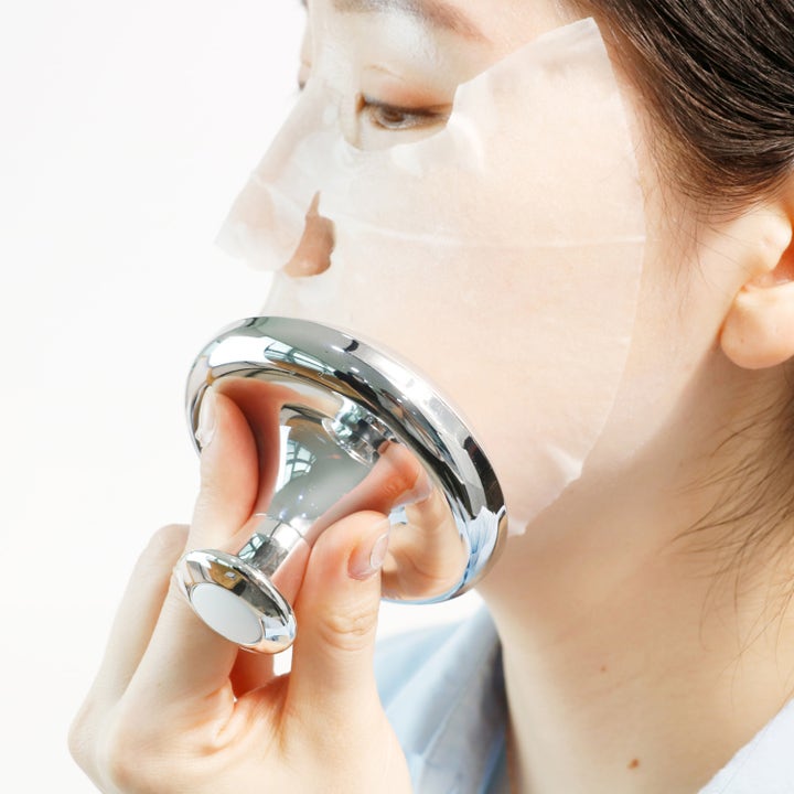 Dr. Ceuracle Cryo Tool 1 stk beroliger huden med kølende massageværktøj i sølvmetal over en sheet maske.