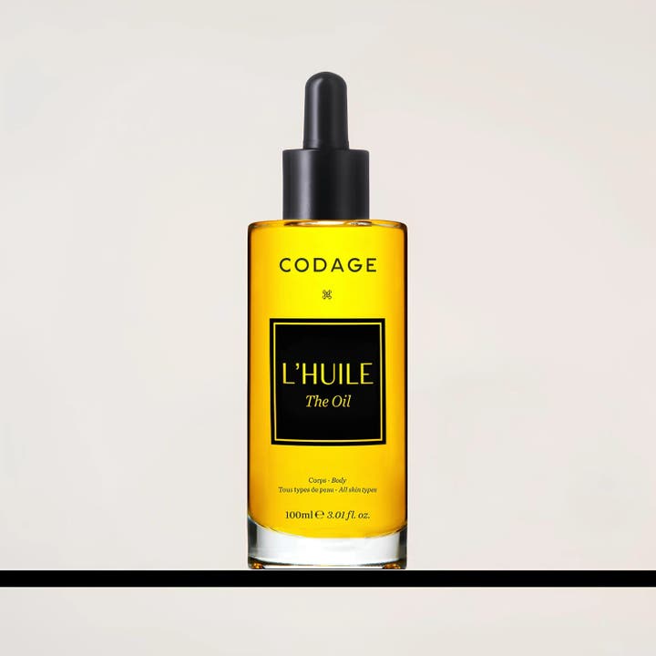 Codage Paris The Oil 100 ml nærende kropsolie i en klar glasflaske med gylden olie og sort pipette.