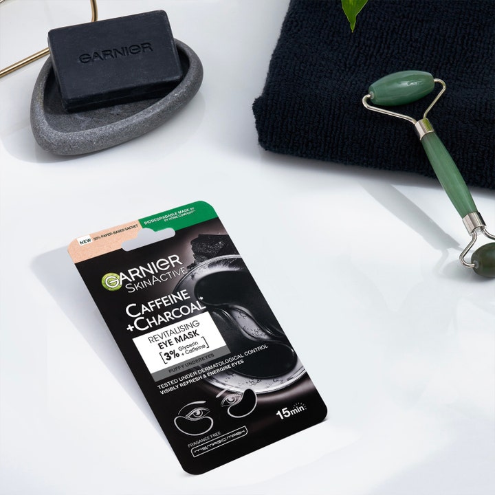 Garnier Skin Active Caffeine + Charcoal 5 g revitaliserende øjenmaske mod hævede øjne vist med en grøn jaderulle.