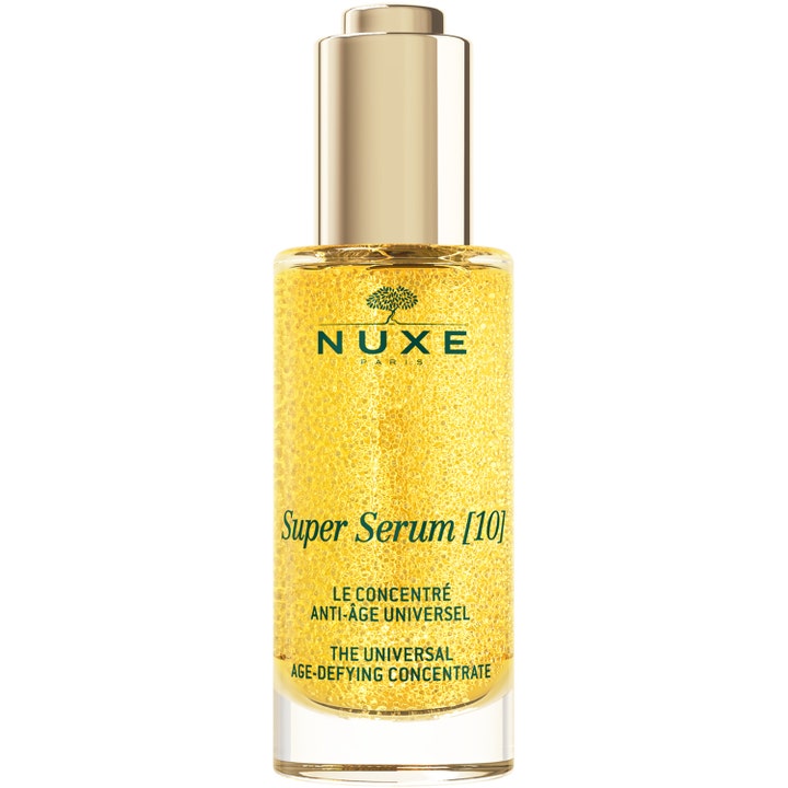 Nuxe Super Serum [10] anti-age serum i glasflaske med guldlåg og tekstur af gyldne mikrosfærer.