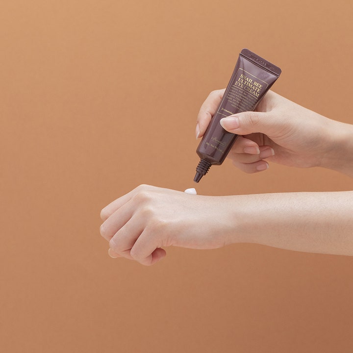 Benton Snail Bee Ultimate Eye Cream 30 g øjencreme med snigelslim påføres fra den brune tube på en hånd