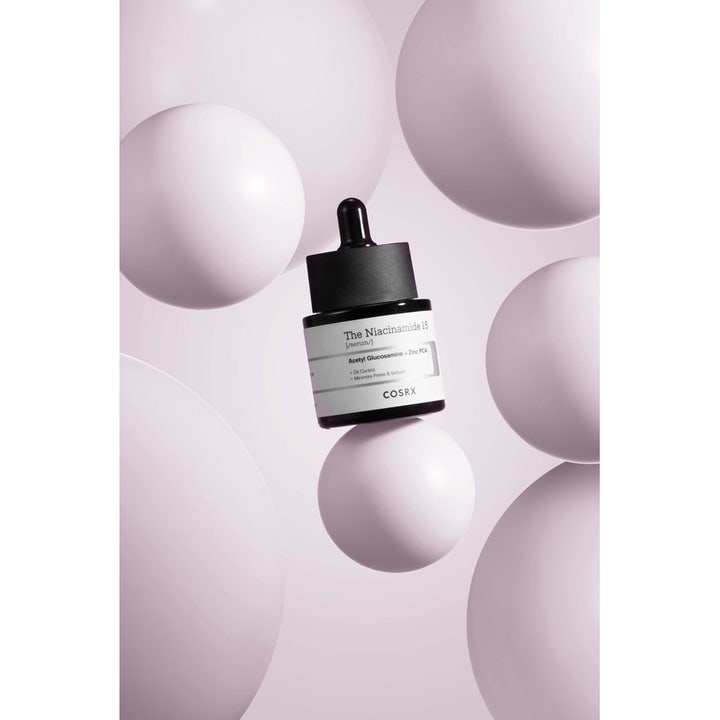 COSRX The Niacinamide 15 Serum 20 ml reducerer porer og talg i mørk glasflaske blandt lyselilla bobler