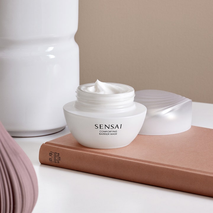 Sensai Comforting Barrier Mask 60 ml beroligende ansigtsmaske med cremet tekstur i hvid krukke på en bog.