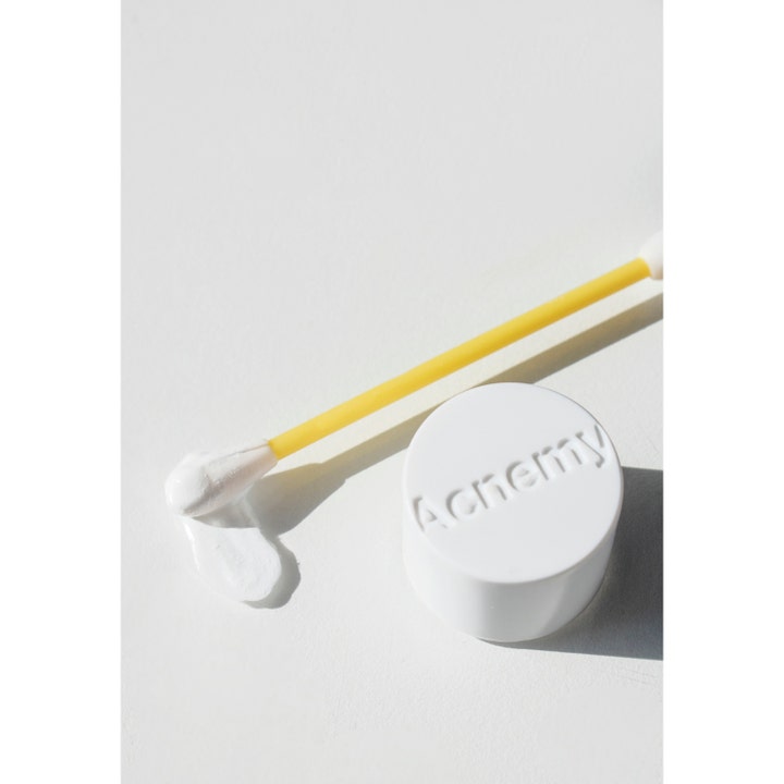 Niche Beauty Lab Acnemy Dryzit 30 ml spot treatment viser hvid tekstur på gul vatpind ved siden af hvidt låg.