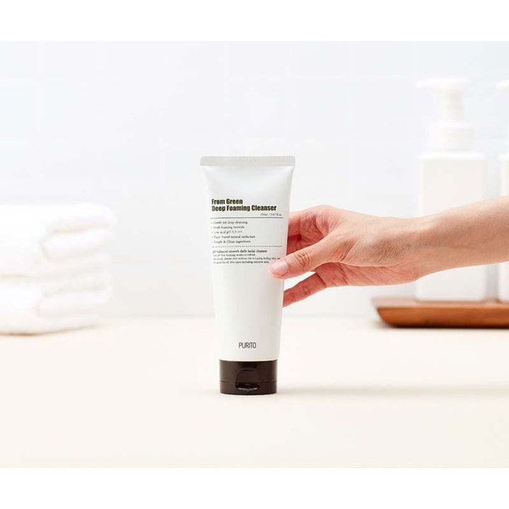 Purito From Green Deep Foaming Cleanser 150 ml ansigtsrens i hvid tube holdt af en hånd i et lyst badeværelse