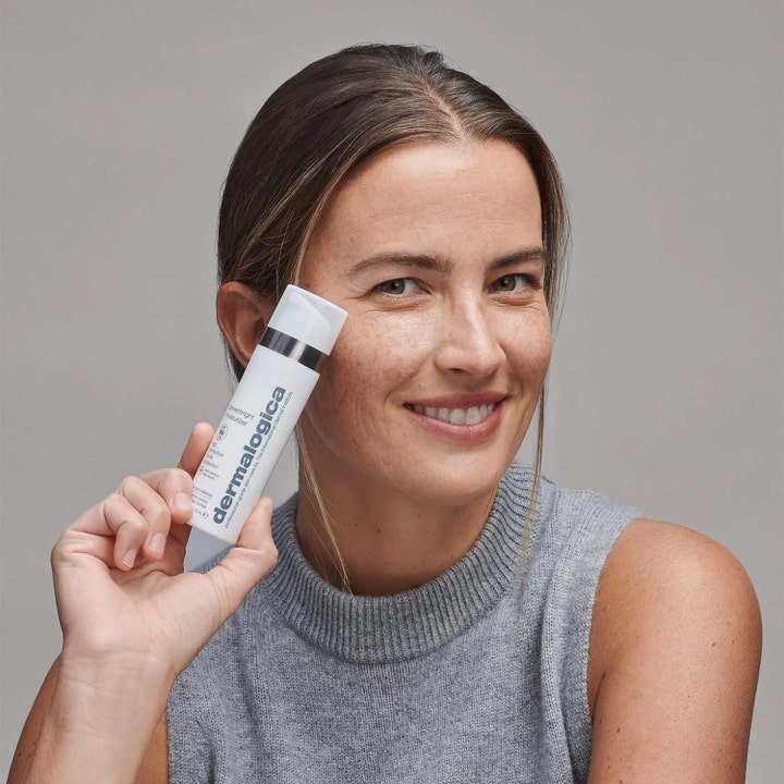 Dermalogica Powerbright Moisturizer SPF50 50 ml i hvid tube holdt af smilende kvinde til daglig pleje.