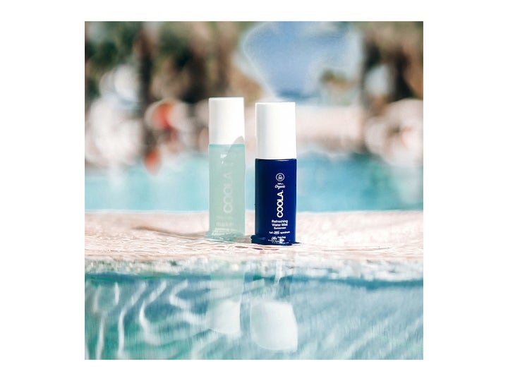 COOLA Refreshing Water Mist SPF15 50 ml fugtgivende face mist i blå flasker ved en solrig poolkant.