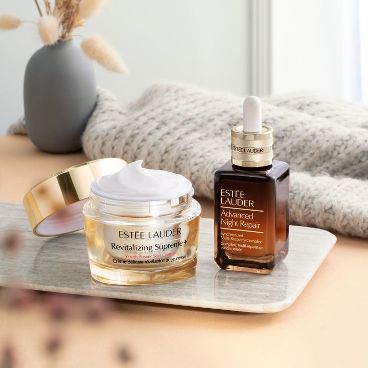 Estée Lauder Revitalizing Supreme+ Soft Cream 50 ml fugtgivende dagcreme i åben guldkrukke ved siden af serum.