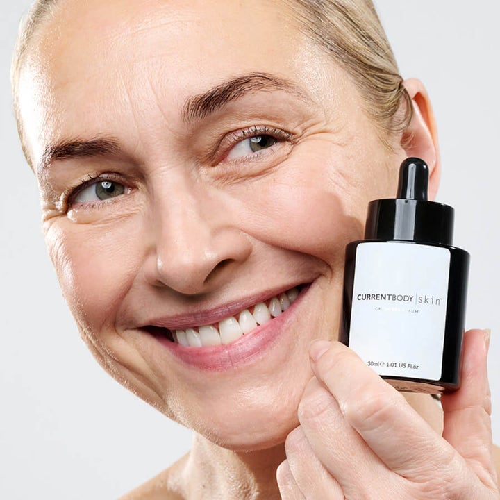 Currentbody Skin Green Tea Serum 30 ml beroligende serum i sort flaske holdt af en smilende kvinde