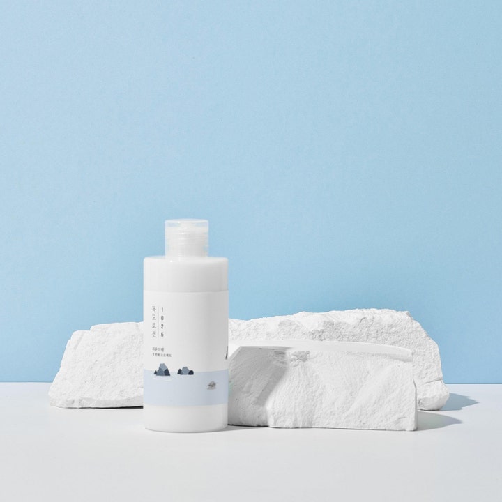 Round Lab 1025 Dokdo Toner Lotion 400 ml fugtgivende ansigtspleje i hvid flaske placeret ved hvide klipper
