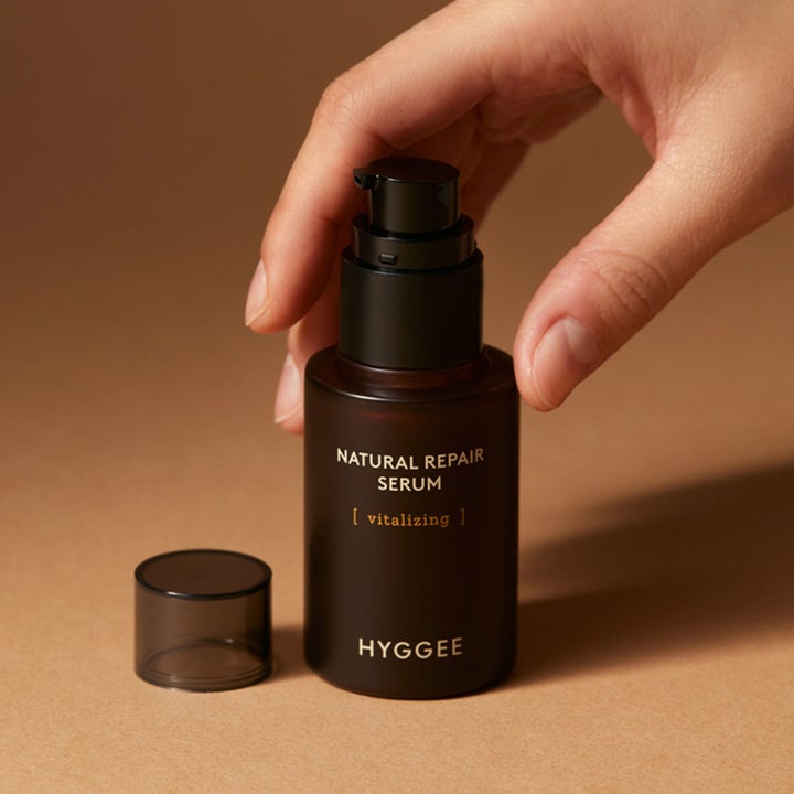 Hyggee Natural Repair Serum 30 ml vitaliserende serum i mørkebrun glasflaske med pumpe holdt af en hånd