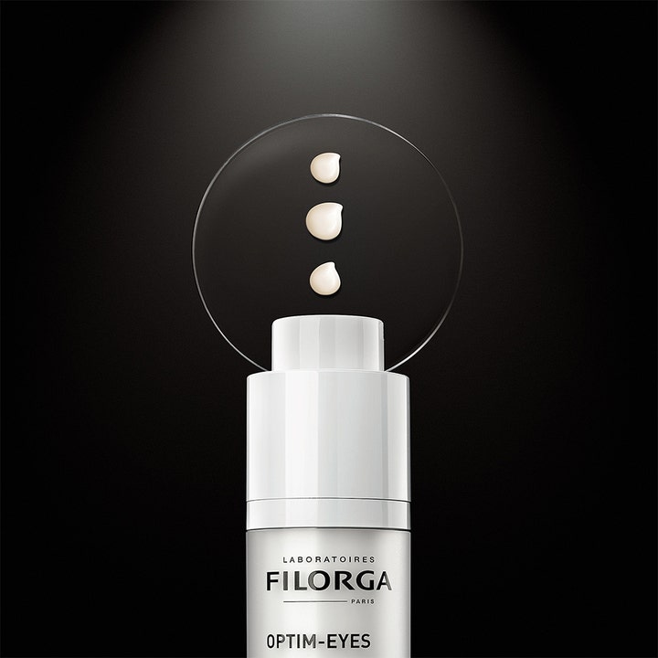 FILORGA Optim-Eyes 15 ml øjencreme mod mørke rande med cremet tekstur vist på en cirkulær glasplade
