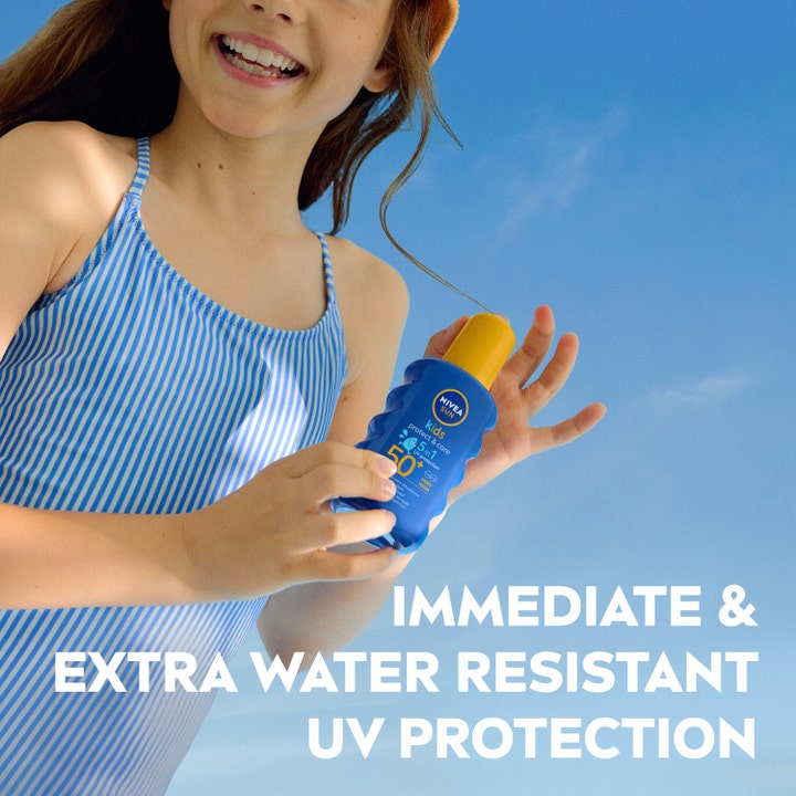 NIVEA Sun Protect & Care Kids Spray 200 ml SPF50+ ekstra vandafvisende solcreme holdes af pige mod blå himmel.