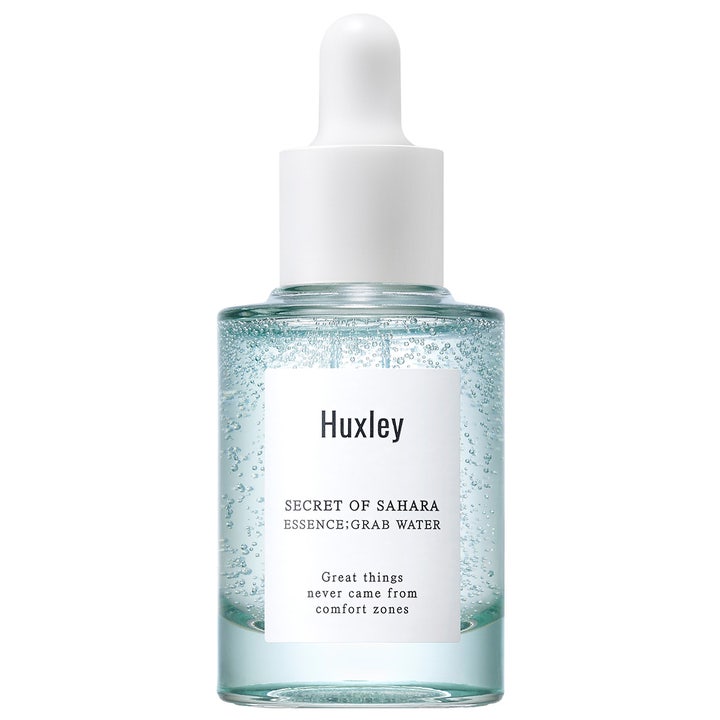 Huxley Secret of Sahara Essence Grab Water 30ml fugtgivende ansigtsserum i glasflaske med hvid pipette og blå luftbobler.